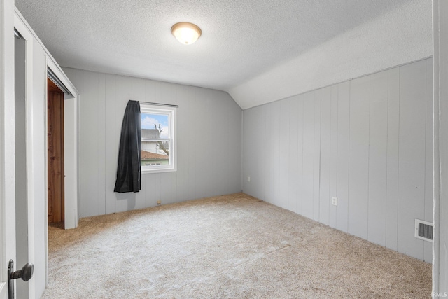 bonus room with lofted ceiling, carpet, visible vents, and a textured ceiling