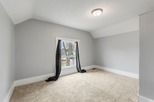 additional living space featuring carpet, vaulted ceiling, a textured ceiling, and baseboards