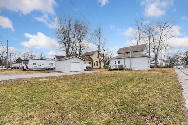 view of yard featuring a garage, an outbuilding, driveway, and a residential view