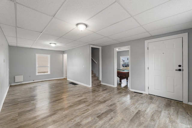 below grade area featuring a paneled ceiling, visible vents, stairway, and wood finished floors