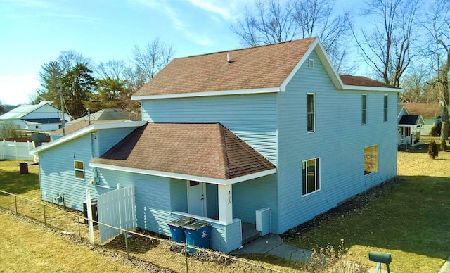 back of house with fence, a lawn, and roof with shingles