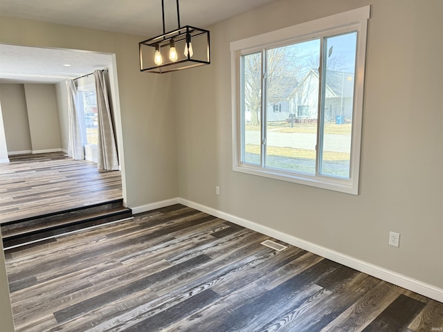 unfurnished dining area with dark wood-style floors, a healthy amount of sunlight, and baseboards