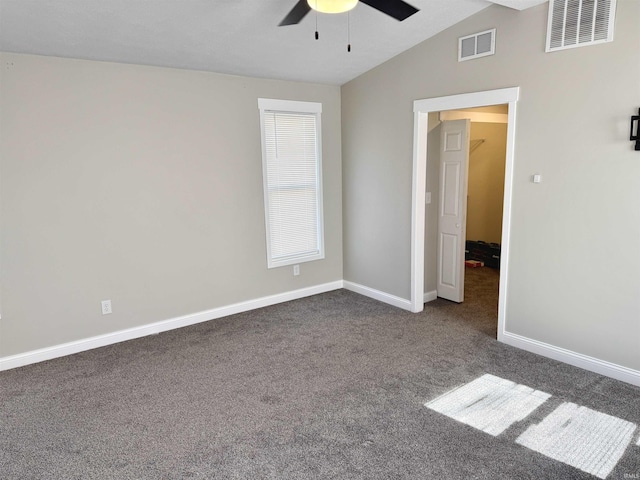 unfurnished bedroom with vaulted ceiling, dark colored carpet, visible vents, and baseboards