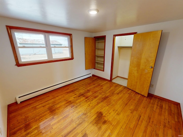 unfurnished bedroom featuring light wood-type flooring, baseboards, and baseboard heating