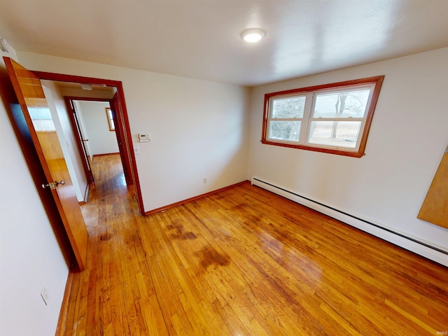 unfurnished bedroom with light wood-type flooring, baseboards, and baseboard heating