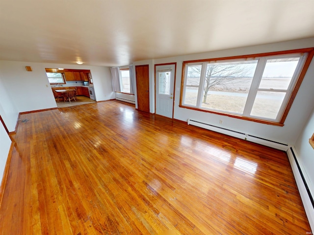 unfurnished living room featuring a baseboard heating unit, a baseboard radiator, light wood-style floors, and baseboards