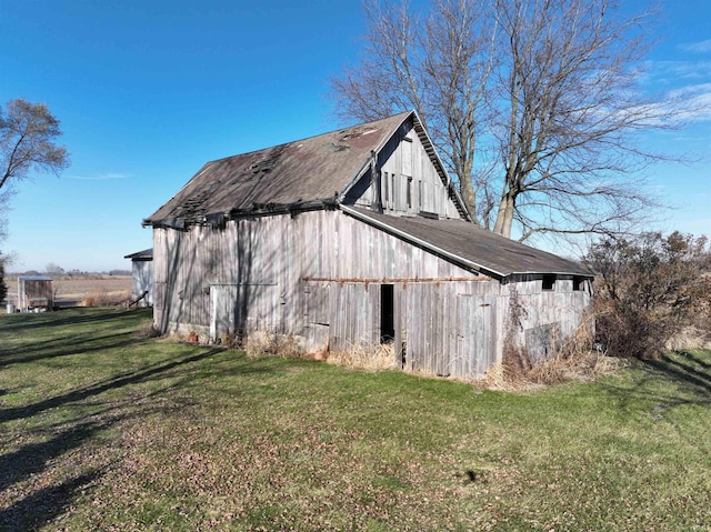 view of home's exterior with a garage, an outbuilding, a lawn, and a barn