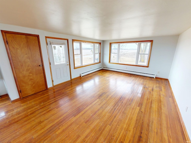 interior space with a baseboard heating unit and light wood-type flooring