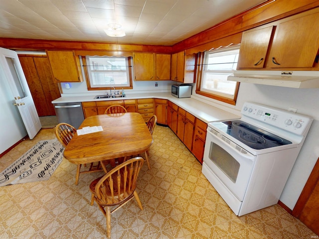 kitchen with brown cabinets, light countertops, appliances with stainless steel finishes, a sink, and extractor fan