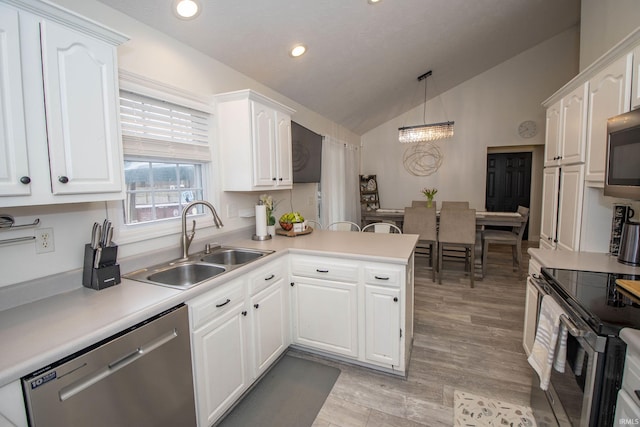 kitchen featuring appliances with stainless steel finishes, white cabinets, a sink, and a peninsula