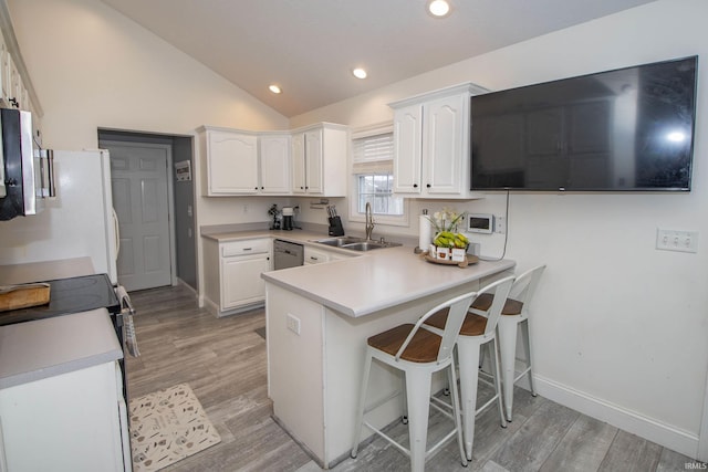 kitchen with stainless steel appliances, lofted ceiling, white cabinets, a sink, and a peninsula