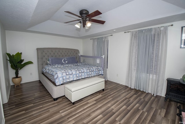 bedroom with a textured ceiling, ceiling fan, a tray ceiling, and wood finished floors