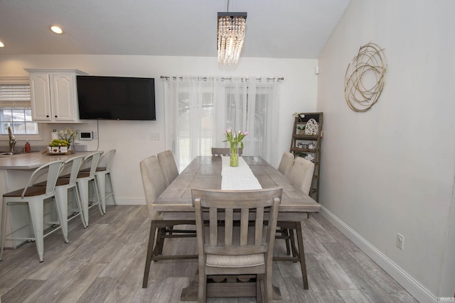 dining area featuring baseboards, light wood-style flooring, and an inviting chandelier