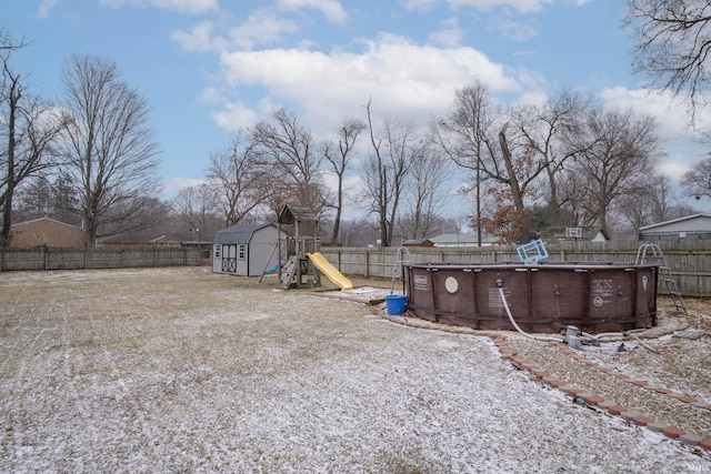 view of yard featuring a fenced backyard, a playground, a fenced in pool, and an outdoor structure