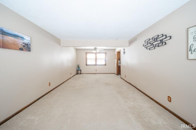 empty room with baseboards, visible vents, a ceiling fan, and light colored carpet