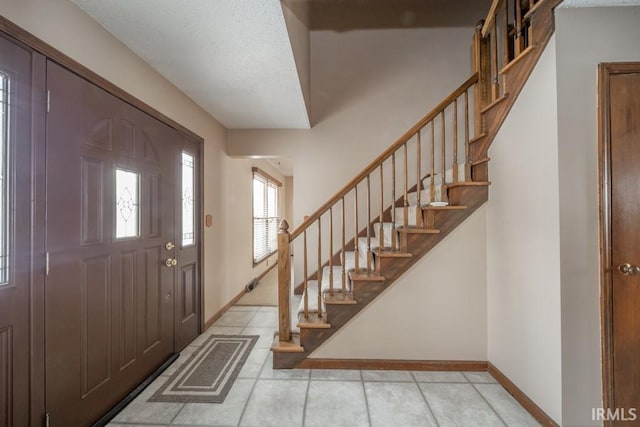 tiled entryway featuring baseboards, stairs, visible vents, and a textured ceiling