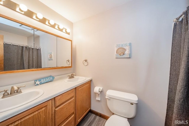 full bathroom with baseboards, a sink, toilet, and double vanity