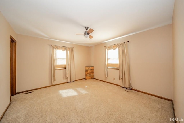 carpeted empty room featuring a wealth of natural light, visible vents, and baseboards