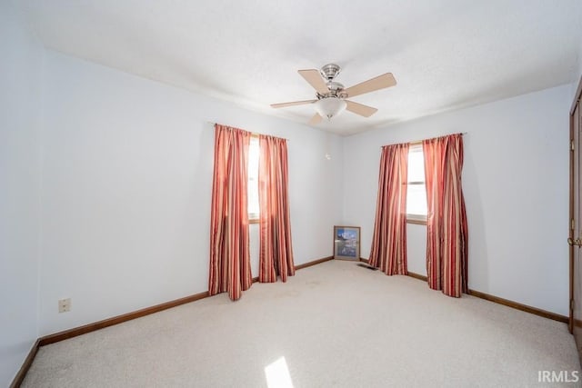 spare room featuring light carpet, a textured ceiling, a ceiling fan, and baseboards