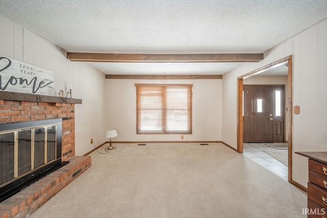 unfurnished living room featuring a textured ceiling, a brick fireplace, beam ceiling, and light colored carpet