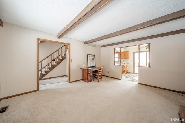 interior space with carpet floors, a textured ceiling, stairway, and beam ceiling