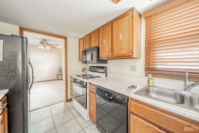 kitchen featuring a ceiling fan, light countertops, a textured ceiling, black appliances, and a sink