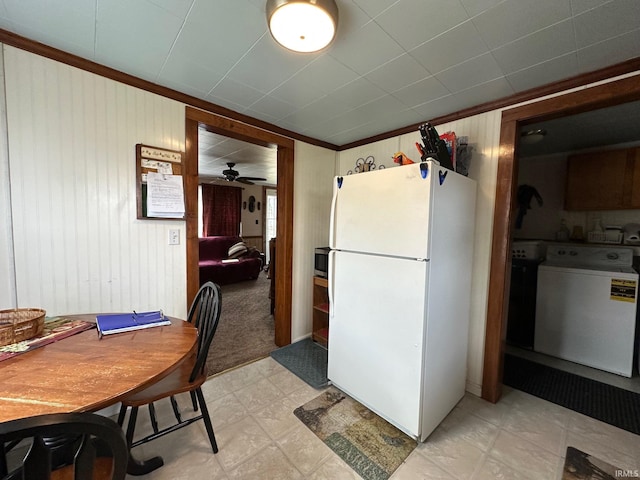 kitchen with wooden walls, freestanding refrigerator, light floors, washer / clothes dryer, and stainless steel microwave