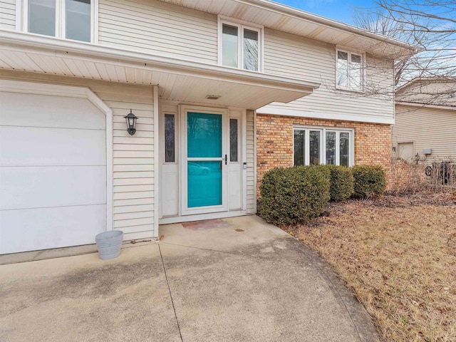 property entrance featuring a garage and brick siding