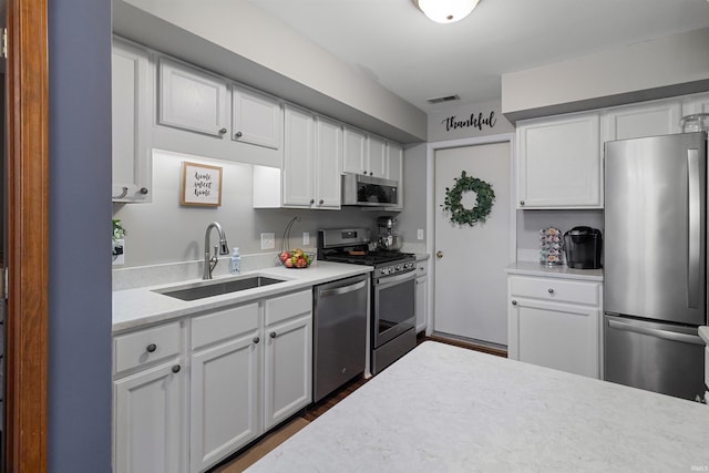 kitchen featuring a sink, visible vents, white cabinets, light countertops, and appliances with stainless steel finishes