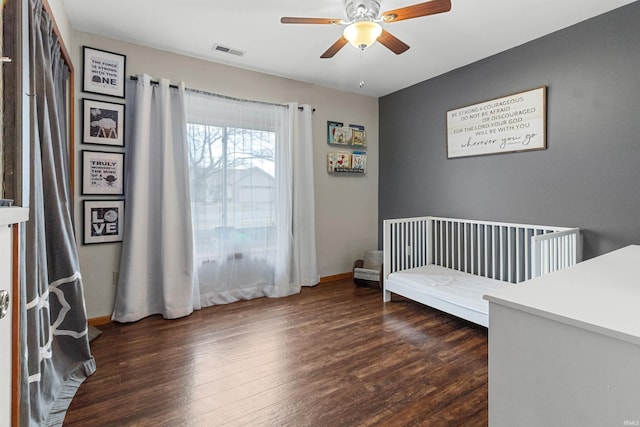 bedroom featuring dark wood-type flooring, a ceiling fan, visible vents, and baseboards