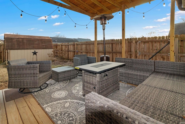 wooden terrace with a fenced backyard, a storage unit, an outdoor hangout area, and an outbuilding