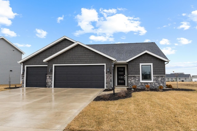 single story home with a garage, a shingled roof, driveway, stone siding, and a front yard