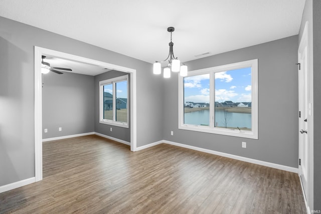 spare room with dark wood-style floors, ceiling fan with notable chandelier, visible vents, and baseboards