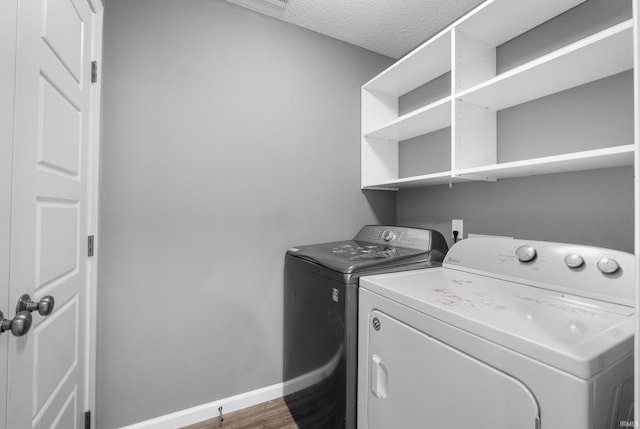 laundry area with washing machine and clothes dryer, dark wood-type flooring, a textured ceiling, laundry area, and baseboards