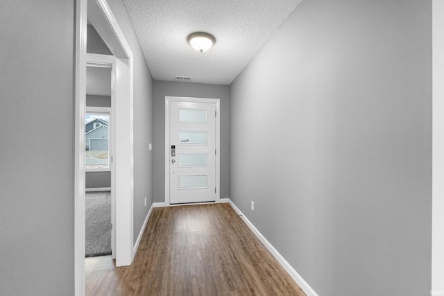 entryway with a textured ceiling, baseboards, and wood finished floors