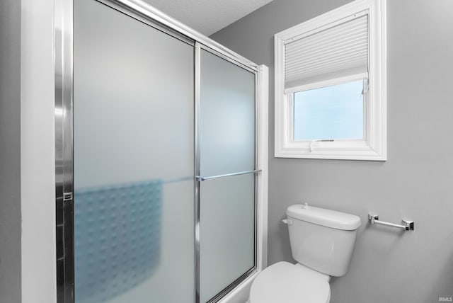 full bathroom featuring a shower with door and toilet