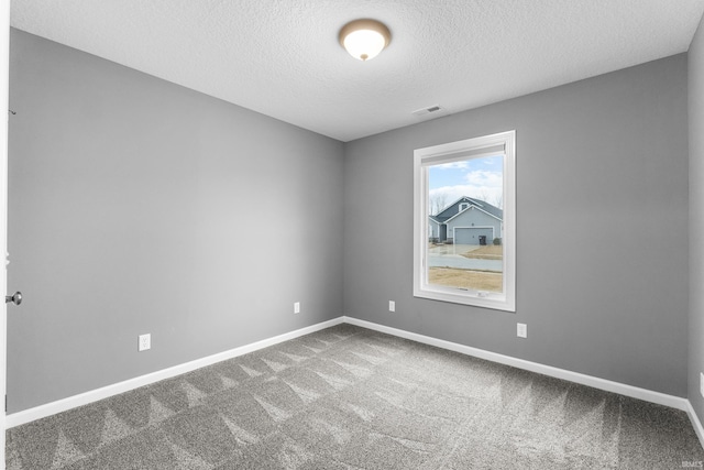 carpeted spare room with visible vents, a textured ceiling, and baseboards