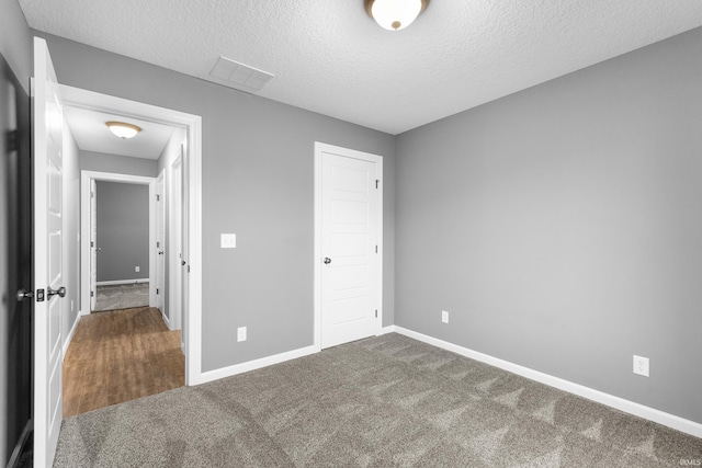 unfurnished bedroom with a textured ceiling, a closet, carpet flooring, and baseboards