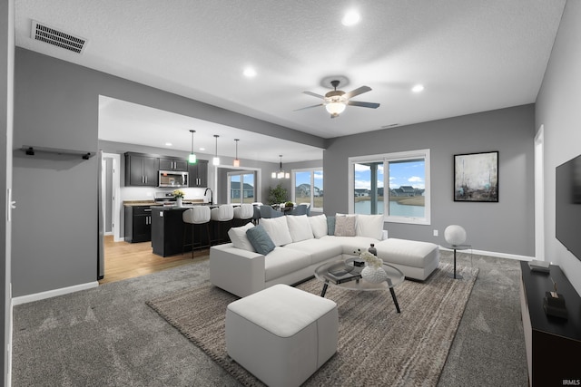 living room featuring recessed lighting, ceiling fan with notable chandelier, light colored carpet, visible vents, and baseboards