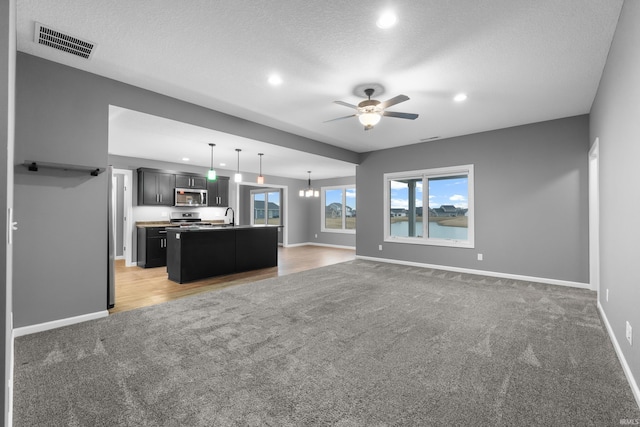 kitchen featuring open floor plan, appliances with stainless steel finishes, visible vents, and light colored carpet