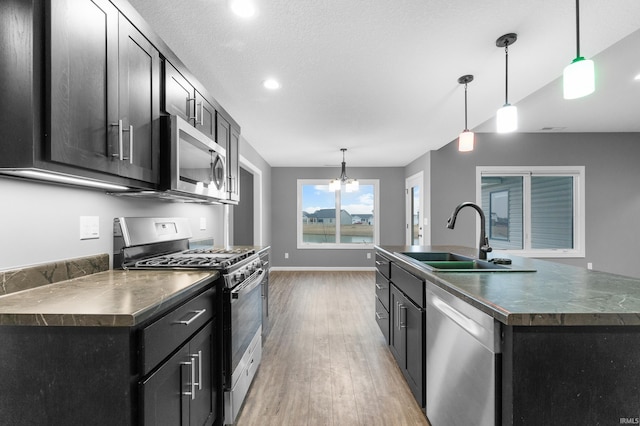 kitchen with appliances with stainless steel finishes, dark countertops, a sink, and dark cabinetry