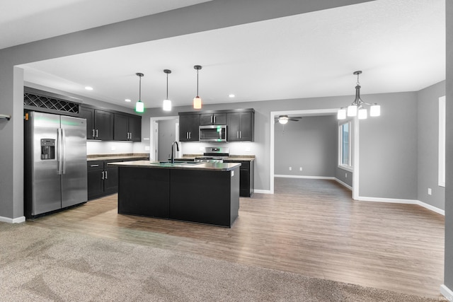 kitchen with stainless steel appliances, dark cabinetry, a sink, and baseboards