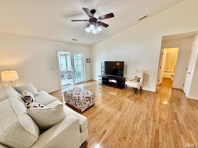 living room featuring light wood-type flooring, baseboards, visible vents, and vaulted ceiling