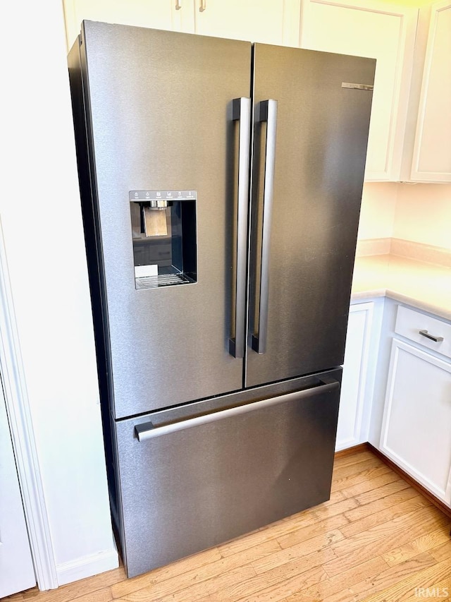 kitchen featuring light wood finished floors, white cabinets, light countertops, and stainless steel fridge with ice dispenser