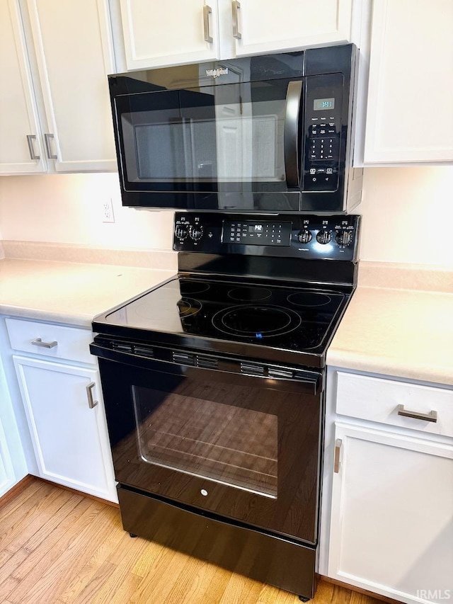 kitchen featuring black appliances, light wood-style flooring, white cabinetry, and light countertops