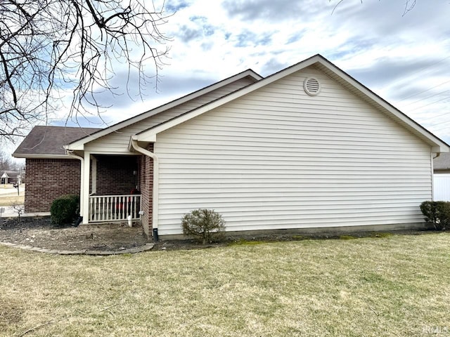 view of home's exterior with brick siding and a lawn