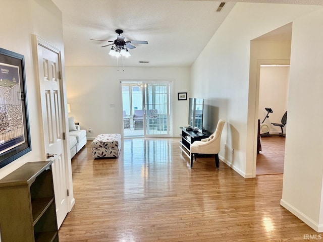 sitting room featuring light wood-style floors, visible vents, baseboards, and a ceiling fan