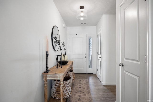 doorway featuring a textured ceiling, visible vents, and wood finished floors