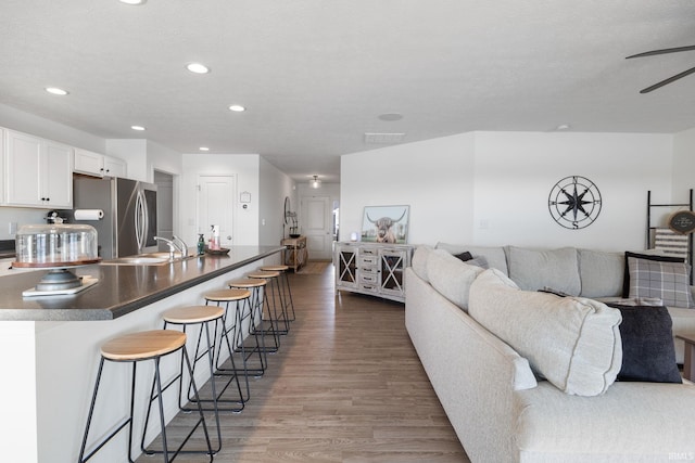 living area featuring a textured ceiling, wood finished floors, a ceiling fan, and recessed lighting