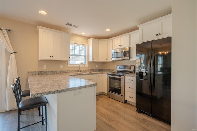 kitchen with light wood finished floors, visible vents, appliances with stainless steel finishes, white cabinets, and a sink